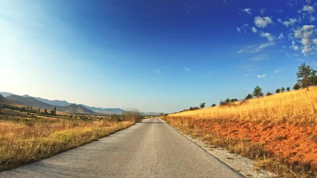 Beautiful countryside, yellow meadows, blue sky with sparse clouds, POV drive