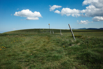 Blauer Himmel auf einem Feld. Hügelige Landschaft und Pfosten, die den Weg markieren.
