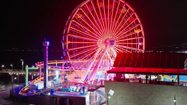 The santa monica pier glows brightly at night with its ferris wheel