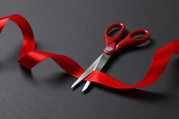 Grand opening invitation card template. Red scissors cutting red silk ribbon on black background
