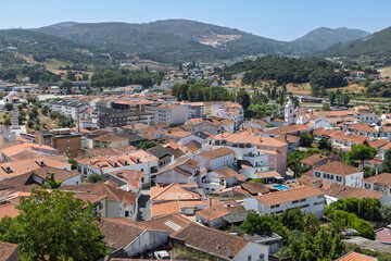 Obraz premium A panoramic view of Porto de Mós, Portugal, from the castle. The town is nestled in a green valley with a backdrop of mountains.