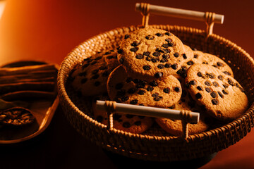 Freshly baked chocolate chip cookies arranged in a wicker basket on a wooden table