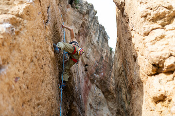 Woman rock climbing a steep cliff using safety rope