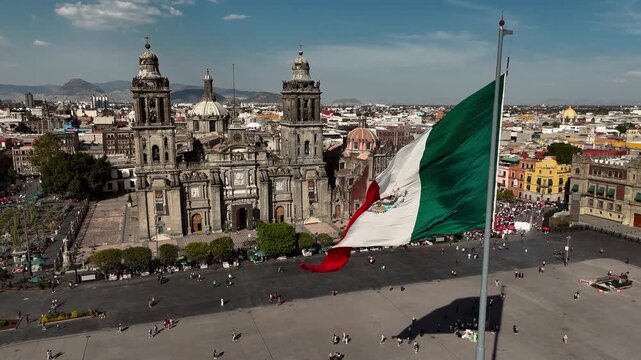 Static shot of the Mexican flag waving in front of the Metropolitan Cathedral at Zocalo square in Mexico City, Mexico
