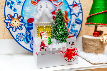 A white plate with a snowman on it sits on a shelf next to a Christmas tree