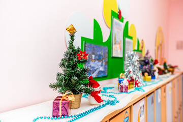 Christmas children's crafts are on shelf. Christmas trees, gifts, Santa Claus - decorated with tinsel and jewelry