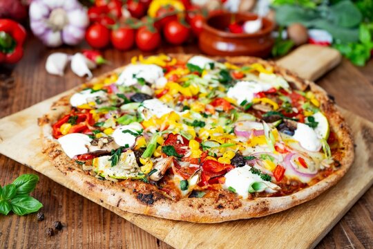 Gesunde hausgemachte Pizza mit Vollkornteig, buntem Gem&uuml;se und Cr&egrave;me fra&icirc;che