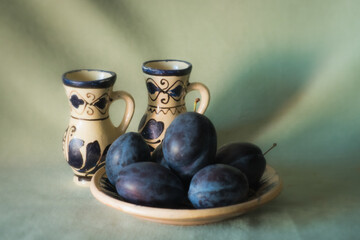 Arrangement with blue purple plums on a light green background