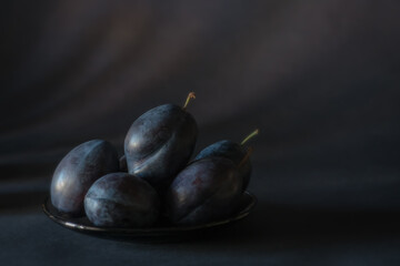Arrangement with blue purple plums on a background of the same color