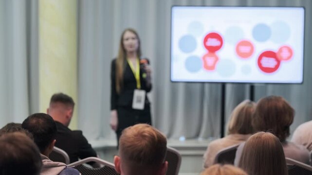 Speaker presenting key points to an attentive audience in a professional conference environment
