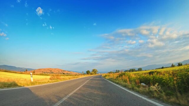 Agricultural nature, POV drive, straight road, fields, blue sky sparse clouds