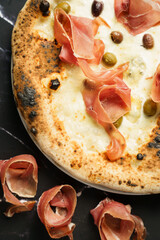 Closeup of prosciutto pizza with olives