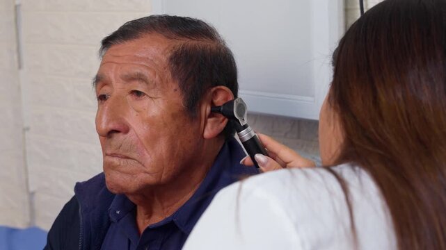 Female audiologist examining a senior man's ear