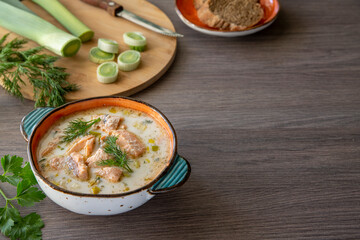 Finnish salmon soup with leek and cream on a wooden table background. Healthy food, traditional food.