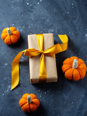 A gift box on a table with knitted pumpkins. Thanksgiving or Halloween gift concept top view