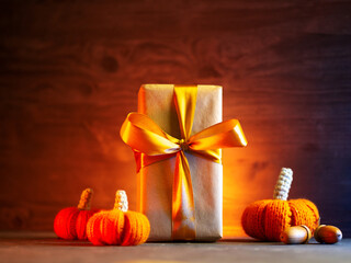 Gift box on a table with knitted pumpkins for Thanksgiving or Halloween.