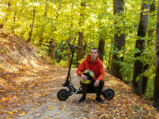 A man on an electric scooter in a colorful autumn forest. Eco-friendly modern transport.