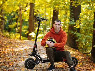 A man on an electric scooter in a colorful autumn forest. Eco-friendly modern transport.