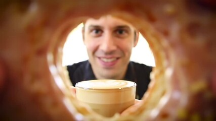 A man peeking through the hole of a donut, enjoying a fun and quirky moment while having a bite."