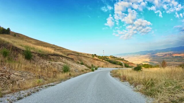 POV downward car drive, mountain slope, beautiful valley view, blue sky