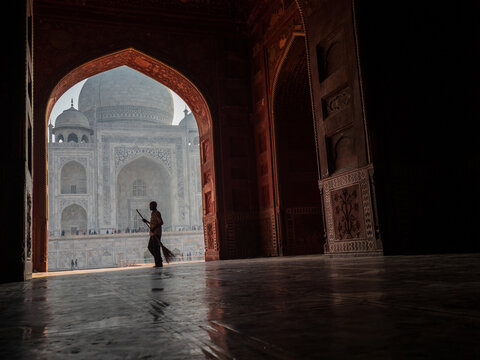 Sweeper Framing Taj Mahal in Red Sandstone Arch, copy space