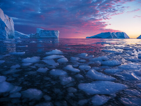 Stunning sunset over the icy waters of Disko Bay with icebergs and floating ice pack, Ilulissat, Greenland