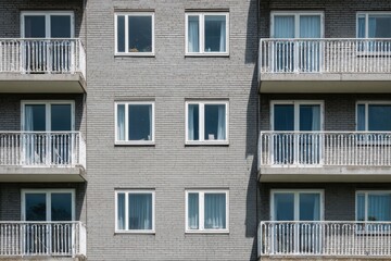 Fototapeta premium Modern apartment building with multiple balconies and large windows showcasing urban living and contemporary design in a city neighborhood during daylight hours