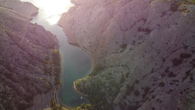Aerial view of a dramatic canyon with turquoise water surrounded by rugged rocky cliffs and sparse vegetation, taken in Croatia