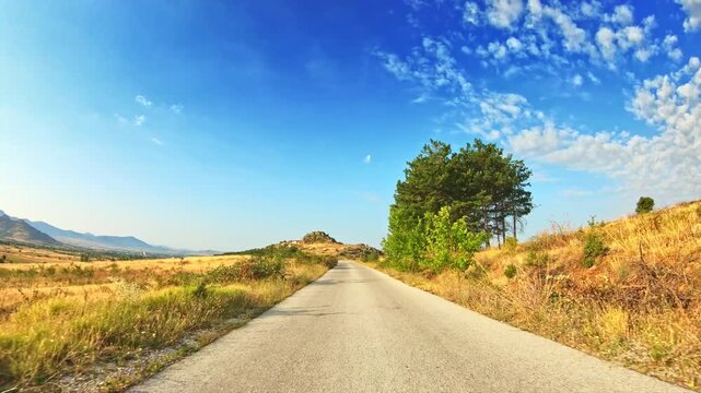 Beautiful nature, rolling countryside, golden meadows, blue sky, POV drive