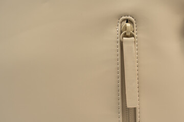 Close-up of beige backpack zipper on a white background. The shot highlights waterproof stitching and pull tab. © Jakob