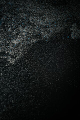 Abstract view of white and blue particles floating against a black background, resembling stars in space or underwater bubbles in darkness.