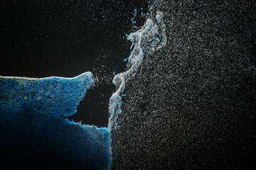 Abstract view of white and blue particles floating against a black background, resembling stars in...