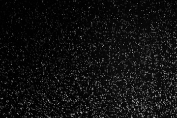 Black and white abstract image resembling snowfall at night or a starry sky, with countless white specks scattered across a dark background.
