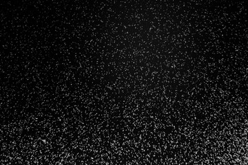 Black and white abstract image resembling snowfall at night or a starry sky, with countless white...