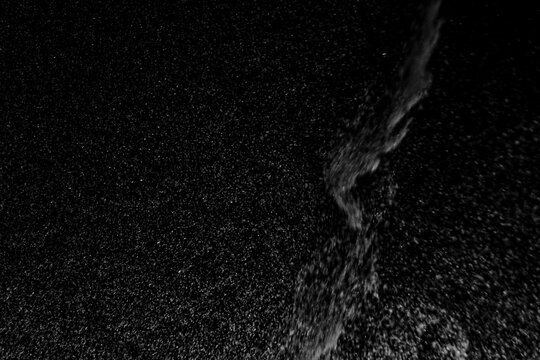 Abstract view of white and blue particles floating against a black background, resembling stars in space or underwater bubbles in darkness.