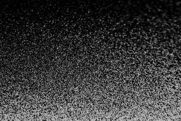 Black and white abstract image resembling snowfall at night or a starry sky, with countless white...