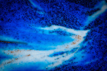Abstract image in deep blue shades with black specks, resembling an ocean wave, galaxy swirl, or cosmic nebula with flowing textures.