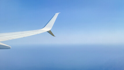 Airplane wing against a clear blue sky, showcasing the vast ocean below. Ideal for travel and aviation themes, capturing the essence of flight and adventure.