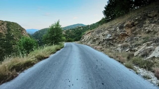 Hilly scenery, POV vehicle drive on narrow road, steep mountain slopes