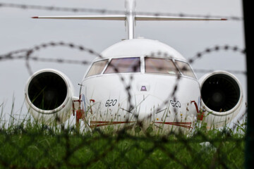 grounded airplane behind a fence