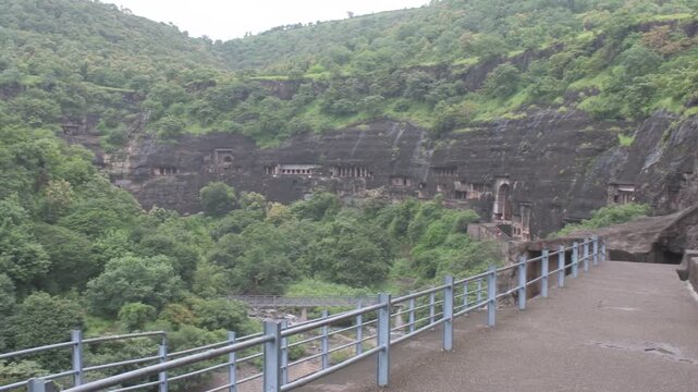 Ancient rock-cut Ajanta Caves nestled into the Sahyadri hill slopes, surrounded by dense seasonal green forests