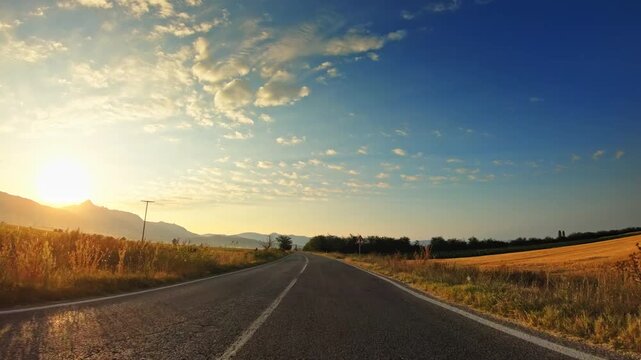 Beautiful sunset, golden valley fields, clouds, POV driver perspective
