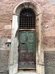 Authentic Italian architecture detail with a weathered wooden door framed in a stone wall. Ideal for cultural, architectural, and travel projects.