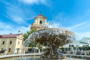 Fountain in front of historic building. Elegant fountain with flowing water in front of old stone architecture under clear blue sky in charming European town.