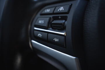 Detailed view of control buttons on the BMW X6 steering wheel, featuring cruise control and lane keeping assist with a black and silver design.