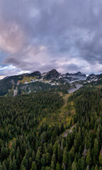 Obraz premium Snowy Mountain Ridge Over Dense Evergreen Forest in British Columbia, Canada at Dusk