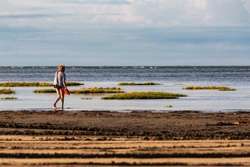 paesaggio costiero all'alba con donna che passeggia sulla riva