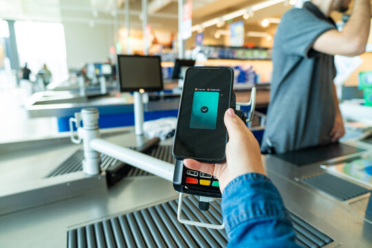 Person using smartphone for contactless payment at supermarket