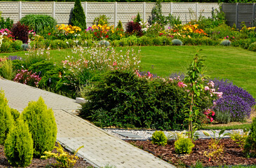 piękny ogród, zielony trawnik w ogrodzie otoczony krzewami ozodbnymi i kolorowymi kwiatami, chodnik w ogrodzie, kompozycja rabatowa, iglaki w ogrodzie, beautiful garden, designer garden, lawn	