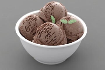 Indulge in creamy chocolate ice cream scoops perfectly garnished with fresh mint leaves in a clean white bowl for a delightful summer treat.